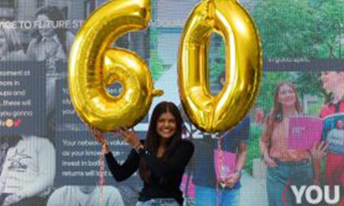 Girl holding golden '6' and '0' balloons