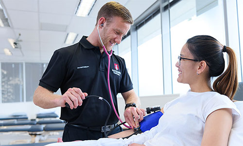 A medical practitioner with a stethoscope and a patient wearing a blood pressure cuff.