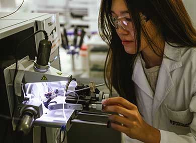 A researcher looking in a microscope, within a laboratory