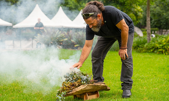 Dharug Elder Uncle Chris Tobin performing a Smoking Ceremony on the lawn.
