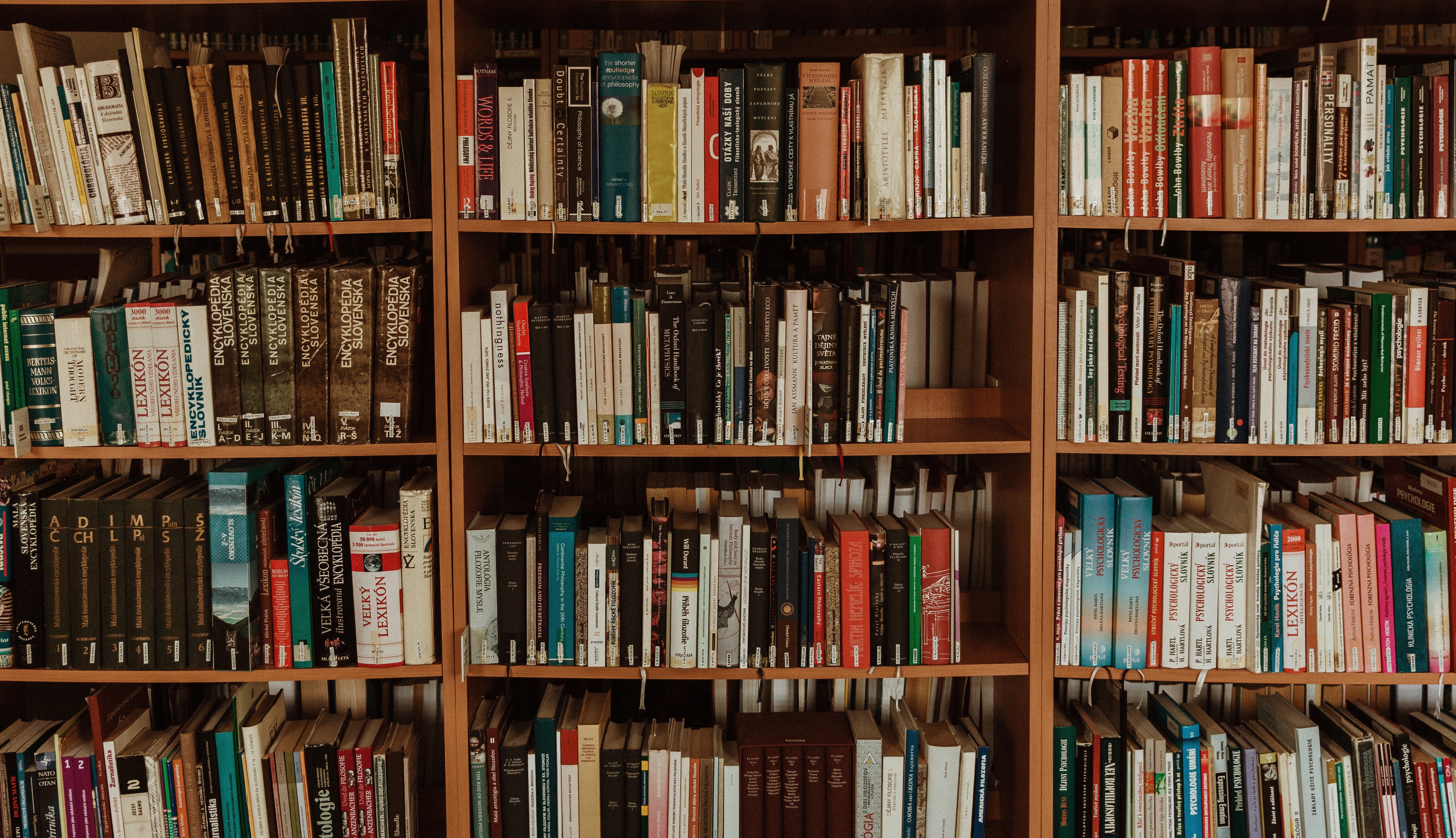 Photograph of three wooden library bookshelves, each with four shelves. 