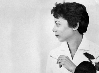 Filmmaker Shirley Clarke holding a cigarette while facing left.