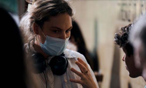 A person wearing a mask and headset while talking on a film set.