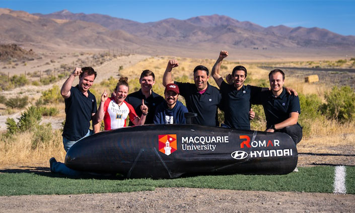 The MQ speed team celebrating behind vehicle in Nevada desert