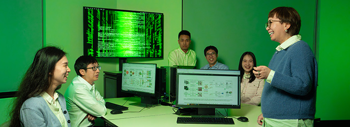 Three students in a computer lab looking at drone footage.