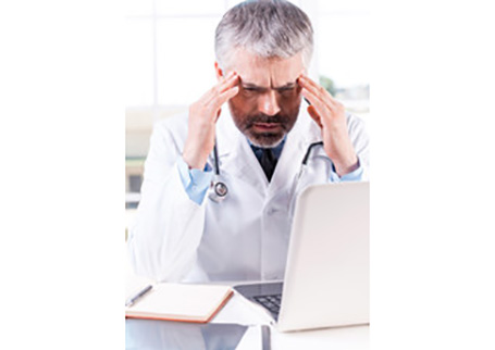 A doctor frowning in front of his laptop