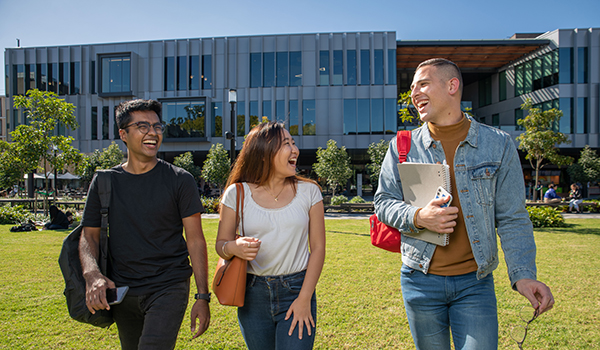 Three students walking on campus grounds