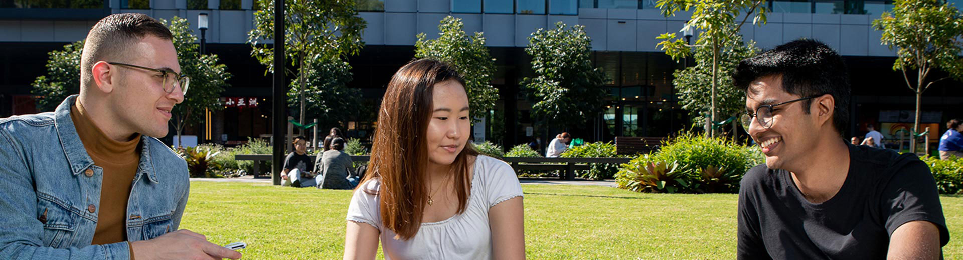 Three students sitting on the grass