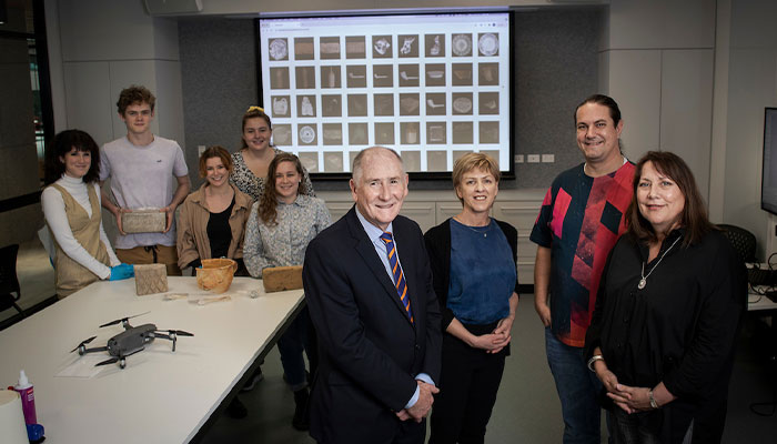 several people standing in a room with artefacts and 3d scanning equiptment