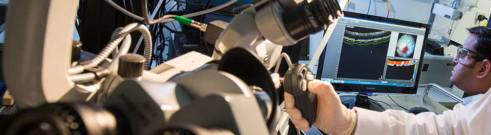Two researchers using microscopes and other laboratory equipment.