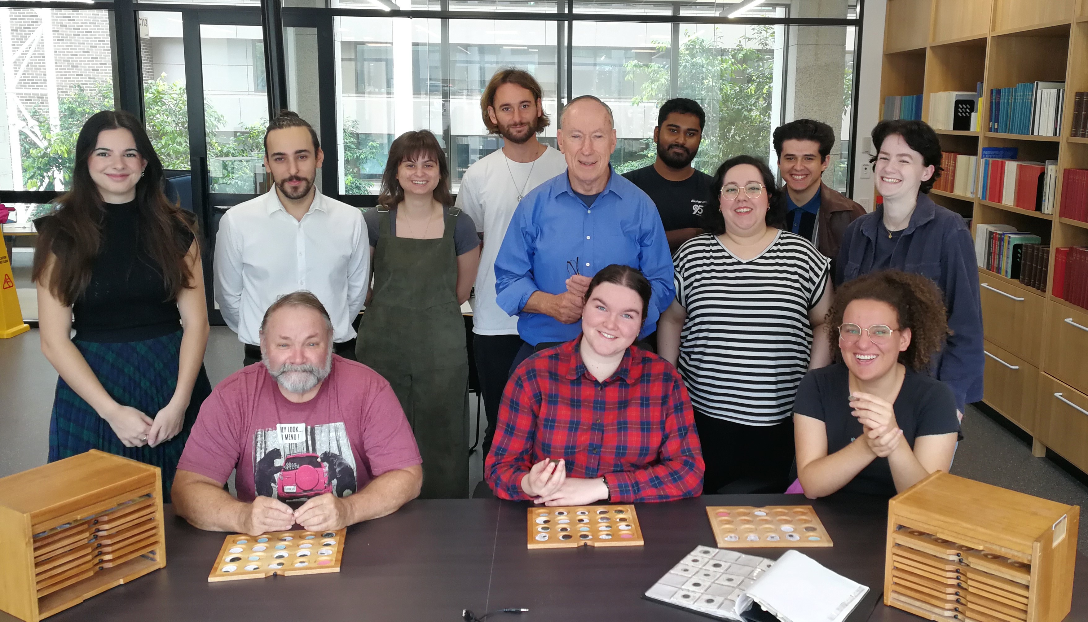 Group of smiling ACANS volunteers with coin trays and boxes in front of them  