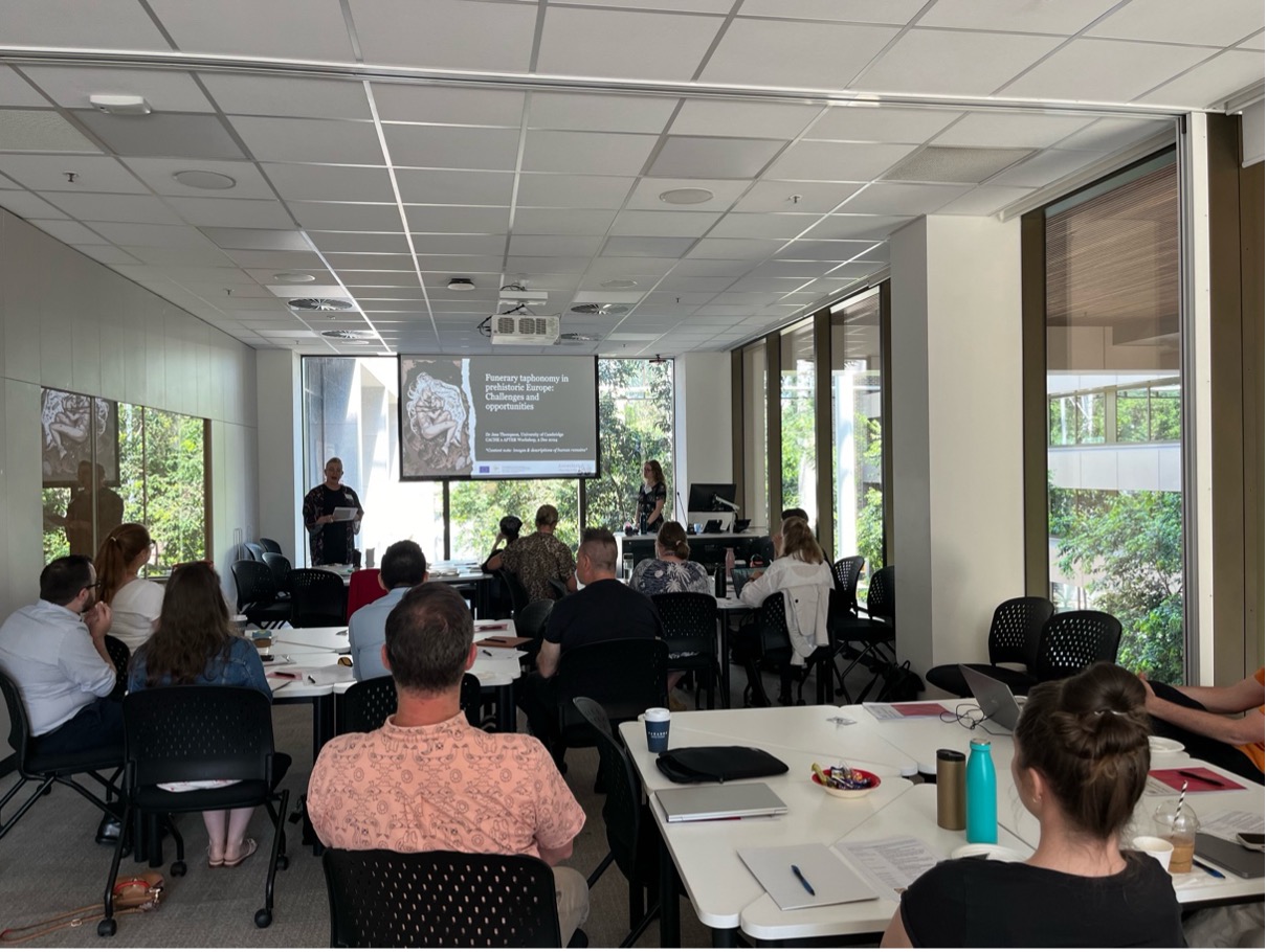 Many people seated around a room looking at a lecture slide projected on the wall. Prof Ronika Power, CACHE Director, introducing the keynote lecture on Bioarchaeological Taphonomy by 2024 CACHE Visiting Scholar, Dr Jess Thompson (Cambridge) at the CACHE X AFTER Collaboration Scoping Workshop