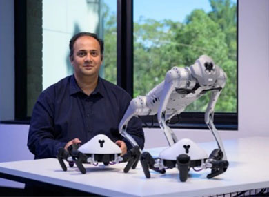 Dr Adnan Mahmood standing with robots