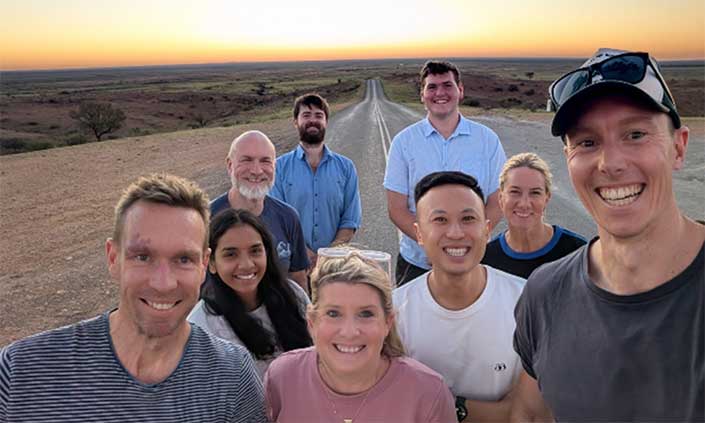 Nine of the people involved standing on a outback highway with the road stretching far back behind them