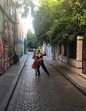 Two people dancing a tango on a cobblestone street