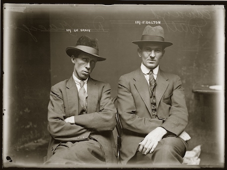 Black and white police mug shot of two seated men