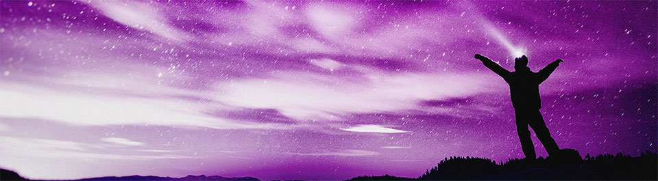 Silhouette of a man on a hill under a sky full of stars