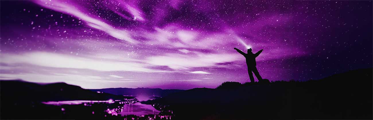 Silhouette of a man on a hill under a sky full of stars
