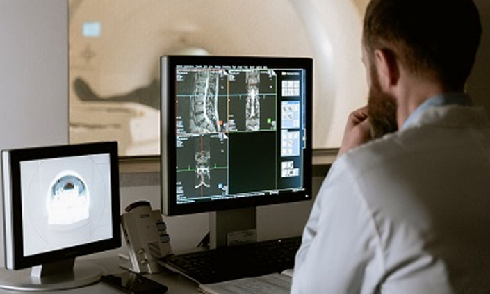 A doctor running a scan looking at two monitors.