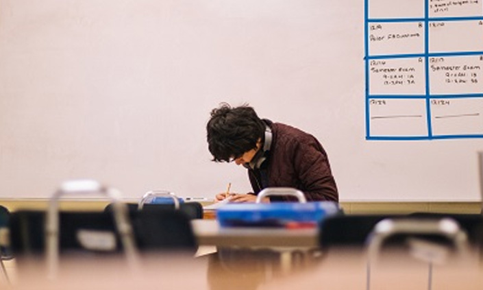 A person in a classroom writing at their desk.