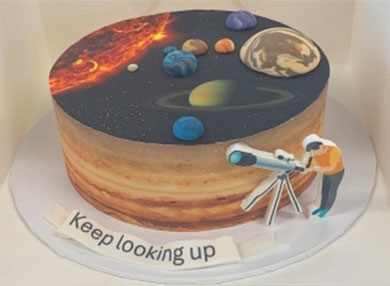 cake with the solar system on it and an astronomer figure using a telescope
