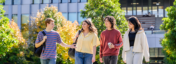 A group of four students walking on the University grounds