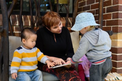 An early childhood educator reads a book with two young children