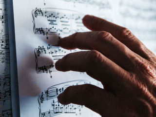 Old hand pointing to music. Photo by Issac Ibbott on Unsplash