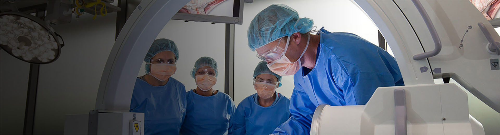 A doctor performing an operation with three trainees watching on
