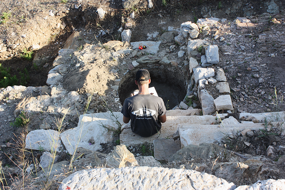 Dr Emlyn Dodd recording the features of a round wine press vat at an archaeological site