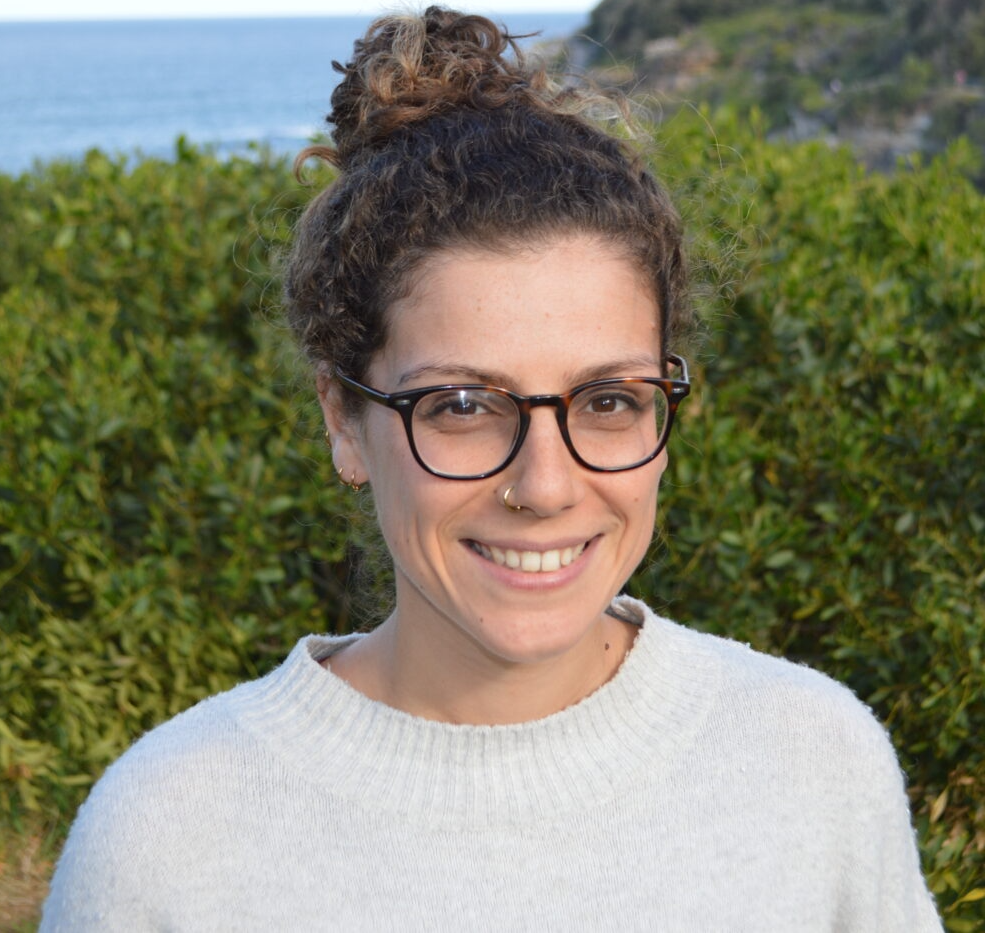 Image of Natalie, a woman in a white top wearing glasses smiling at the camera