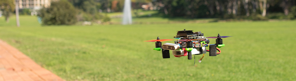 A small drone hovering over the Macquarie University lawn.