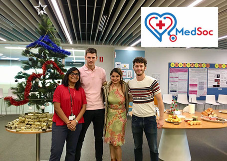 Four researchers at an event, with the Medsoc logo