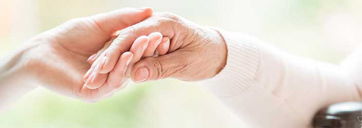 A young hand holding an older woman's hand