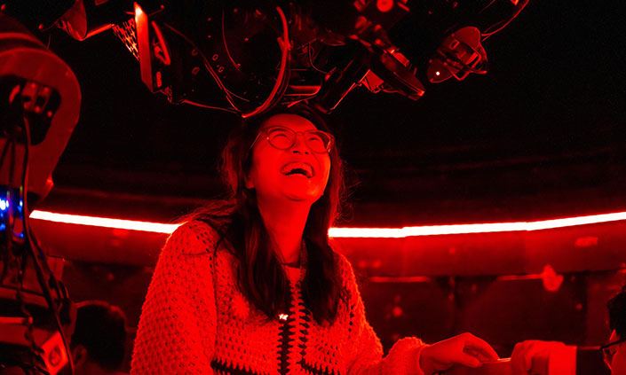 Person looking into observatory and laughing, red strip of light running across background