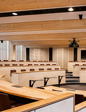 Lecture room with wooden accents and rows of circular terraced seating.