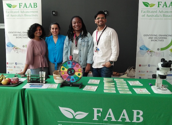 Four FAAB volunteers standing by a green stall table with various activties