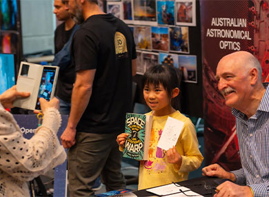 Astronomy Author getting his photo taken with child holding book 