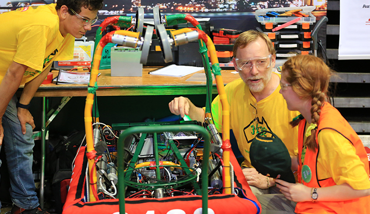  Mentor Graham Allen works with high school students Katherine Allen and Oliver Nicholls to repair the robot 'Maloo' at competition.